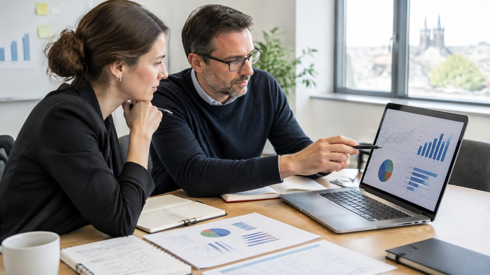 Analysts reviewing statistical charts on a laptop during a meeting